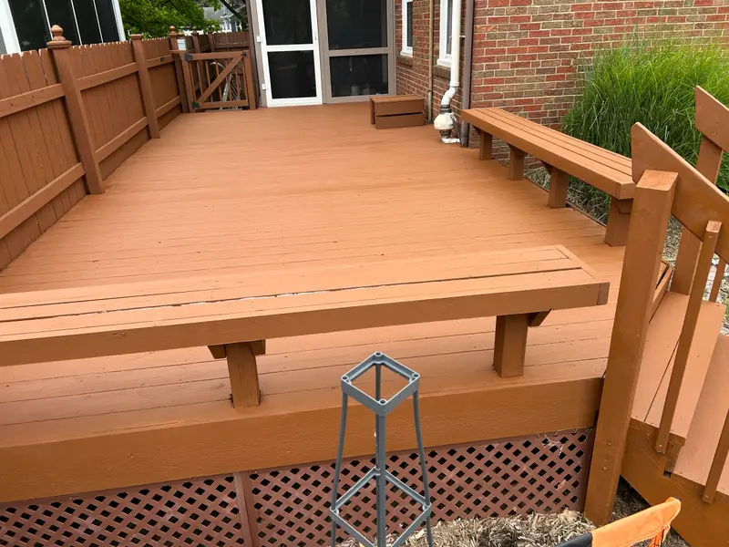 A restored backyard deck finished in a warm cedar tone, with built-in benches and railing