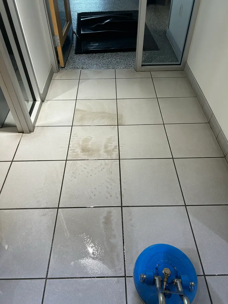 Commercial tile floor part-way through a deep clean, cleaned tile beside still-soiled grout