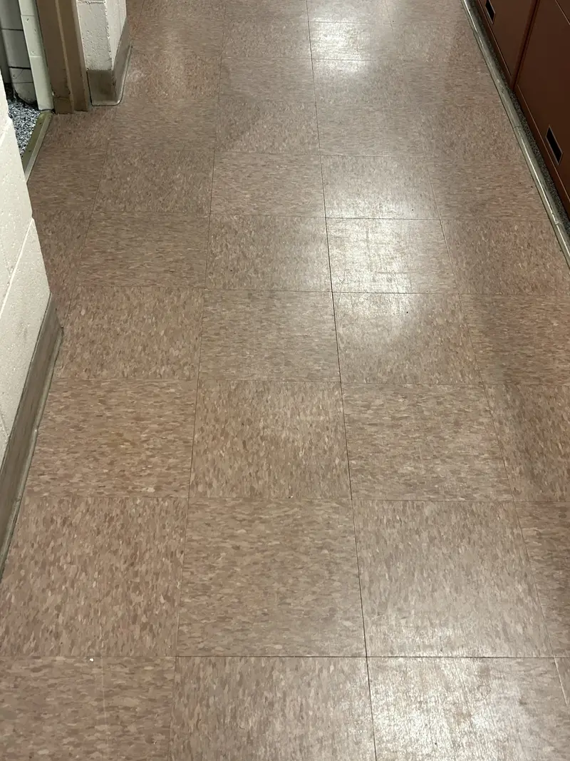 The same VCT corridor before stripping, the finish scuffed and worn dull