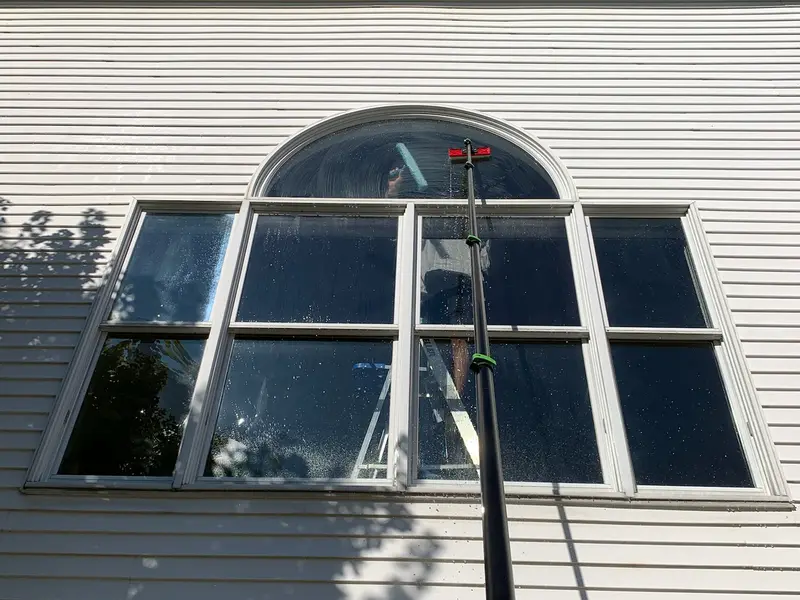 A water-fed pole reaching the arched second-storey window of a Quad Cities home from the ground